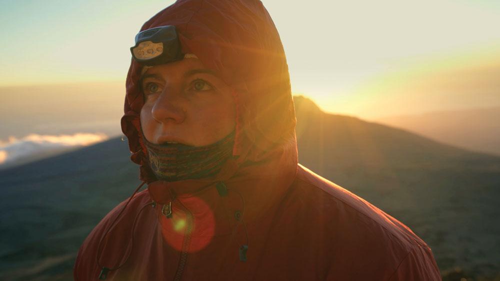 Filmstill from KiliBig of woman on mountain top in a orange coat